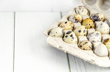 Quail eggs in eco-friendly packaging made from recycled paper, on white wooden table background