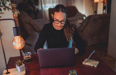 A young girl working from home in her home office and talking on phone about business