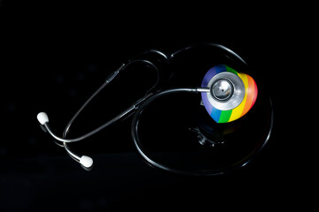 Stethoscope with heart on rainbow love shape hand exercise ball, symbol of LGBT pride celebrate is humanity  equal concept with black background.