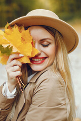 Portrait of a young blonde girl in a beige hat outdoors on autumn