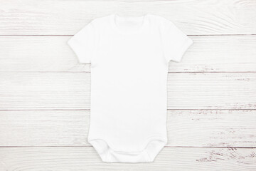 White baby girl or boy bodysuit mockup flat lay on wooden background. Design onesie template, print...