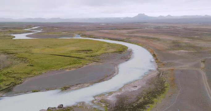Aerial ascending view of winding river Sanda in the desolate highlands of Iceland.