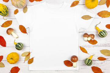 White womens cotton t-shirt mockup with pumpkins, mushrooms and fallen leaves on white wooden...