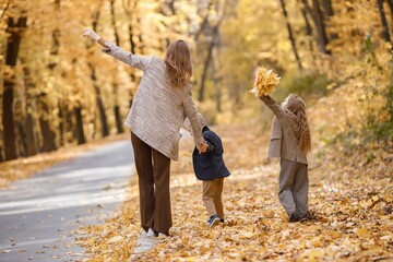 Fototapeta premium Mother and her children playing and having fun in autumn forest