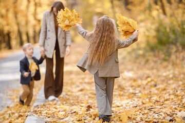 Mother and her children playing and having fun in autumn forest