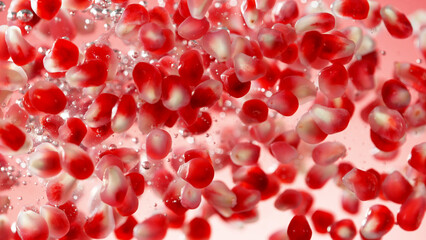 Sweet pomegranate seeds splashing underwater.