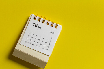 Desktop calendar for October 2022 on a yellow background.