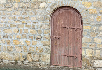 Fototapeta na wymiar An old wooden door in a stone wall.The entrance to the ancient tower.