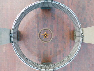 The concept of the memory of the fallen in the war. Top view of the memorial with a star and eternal flame on a sunny day. Bird's-eye view.