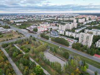 Panoramic view from the drone of a walking park near residential buildings. Urban landscape, bird's-eye view from the park. Cloudy weather over the city.