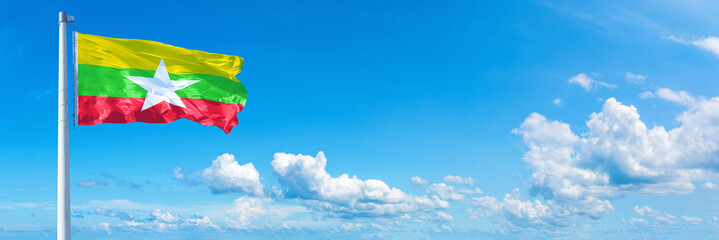 Myanmar flag waving on a blue sky in beautiful clouds - Horizontal banner