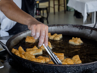 Deep-fried dough sticks or Patongko in Thai, Asian famous street food in Thailand, Chinese doughnuts. A traditional yellow crispy snack made from flour and cooked in pan with hot oil.