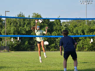 Volleyball coed doubles match girl hitting the ball and boy playing defense