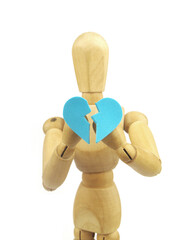 Wooden figurine holding broken heart in hands isolated on white background. Divorce, sickness and...