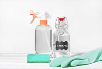 white vinegar for home cleaning chores, natural householding detergent, affordable product for housekeeping, rubber glove and kitchen sponge next to sprayer bottle.
