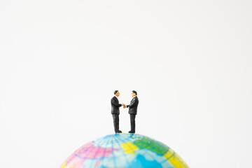 business miniature people shaking hands on world ball toy on white background