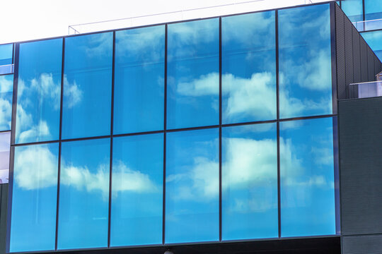 Modern glass building with blue sky and clouds reflection. High quality photo
