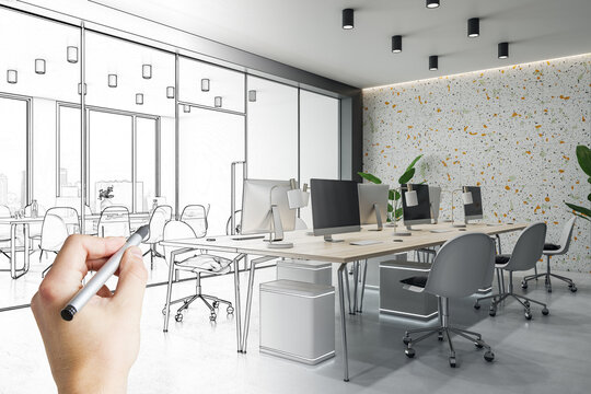 Stylish open space office design project development with multi colored wall, wooden tables, grey chairs and hand drown sketch by human hand with pencil