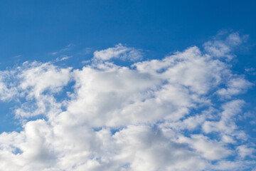 Einige weiße fluffige Cumulus-Wolken vor strahlend blauem Himmel an einem warmen Sommertag als Symbol für Freiheit und Urlaub