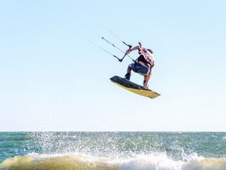 Young man kite boarder jumps over the sea at sunset. Selective focus.