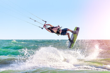 Young man kite boarder jumps over the sea at sunset. Selective focus.