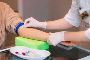 Obraz na płótnie Canvas Preparation for blood test with female doctor in medical uniform on table in white light room. A nurse closes a patient's arm vein with cotton wool after the test.