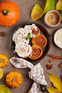 Pumpkin cinnamon rolls. Yeast dough buns in a shape of spiral with sugar and cinnamon filling and cream cheese frosting. Delicious autumn homemade dessert.