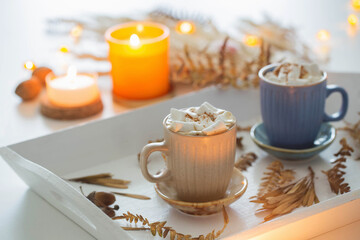 two cups of  coffee  with marshmallows  and autumn decor on white wooden tray