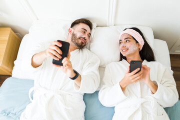 Happy couple doing a skin care routine while relaxing in bed