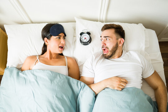 Stressed Couple Waking Up Late In Bed With An Alarm Clock