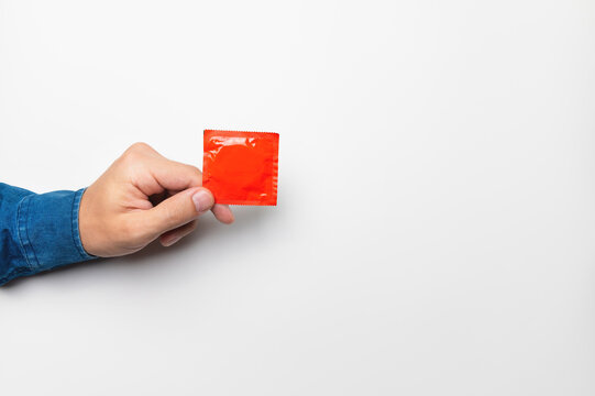 hand with a condom in a red package on a white background, mockup for your advertising