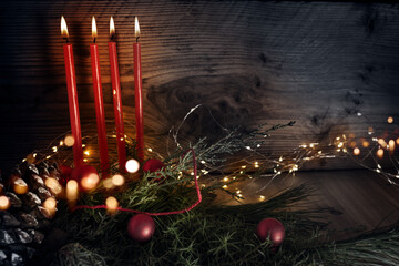 Christmas and advent backgroundwith four red burning candles and natural decoration on rustic wood...