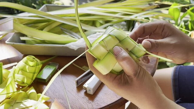 Hands making Tipat Balinese Offering with Coconut Leaves