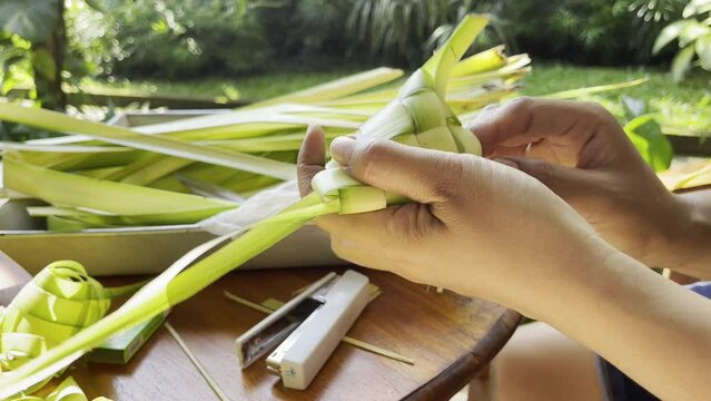 person cutting coconut leaf for offering balinese culture tipat
