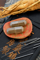 Chinese Medicine acupuncture needles capsules and ginseng root placed on an ink stone.  - 533171905