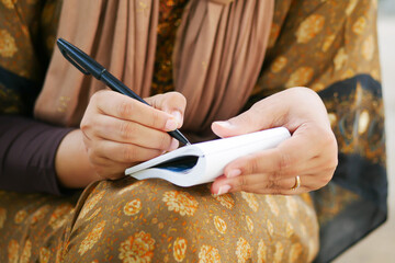 Close up of women hand writing on notepad.