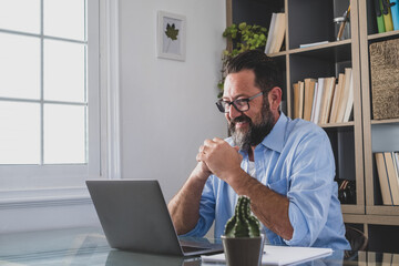 one young man working at home in the office with laptop and notebook taking notes talking in a video conference. One businessman calling communicating.