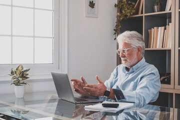 Happy old caucasian businessman smiling working online watching webinar podcast on laptop and...