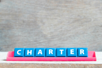 Tile alphabet letter with word charter in red color rack on wood background