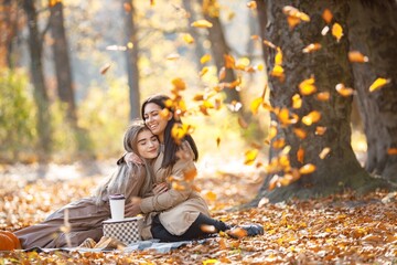 Two girls making picnic on a blanket in autumn park