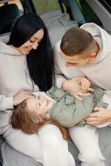 Obraz premium Portrait of a family hugging in a open car's trunk