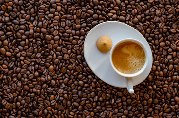 Cup of coffee and coffee beans on table, top view