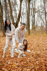 Young family playing in autumn forest and hugging