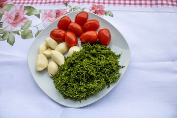 Charry Tomaten mit Knoblauch und Dille oder Kaper in weisse Teller auf dem Tisch