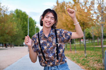 Young Taiwanese man smiling and dancing rock and roll in a park.