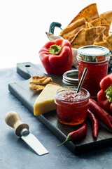 An arrangement of hot pepper jelly with cheese and crackers, lit from behind.
