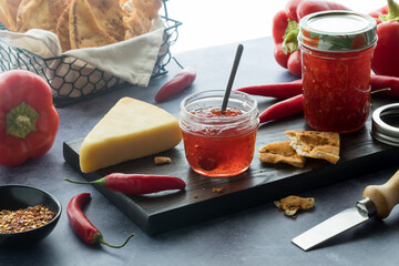 A board with hot pepper jelly served with crackers and cheese, lit from behind.