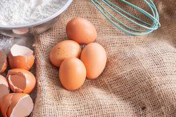 Baking ingredients with eggs, flour and blue whisk . Home baking concept.