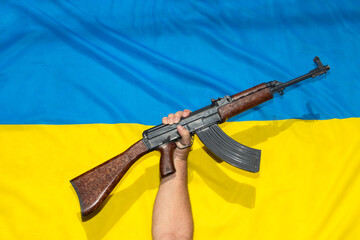 The raised gun in front of Ukrainian flag, symbolizes resistance against the aggressor