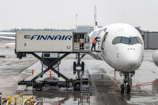 HELSINKI, FINLAND, FEB 15 2022, Workers load carts to an airliner at the snowy Helsinki Airport, Finland